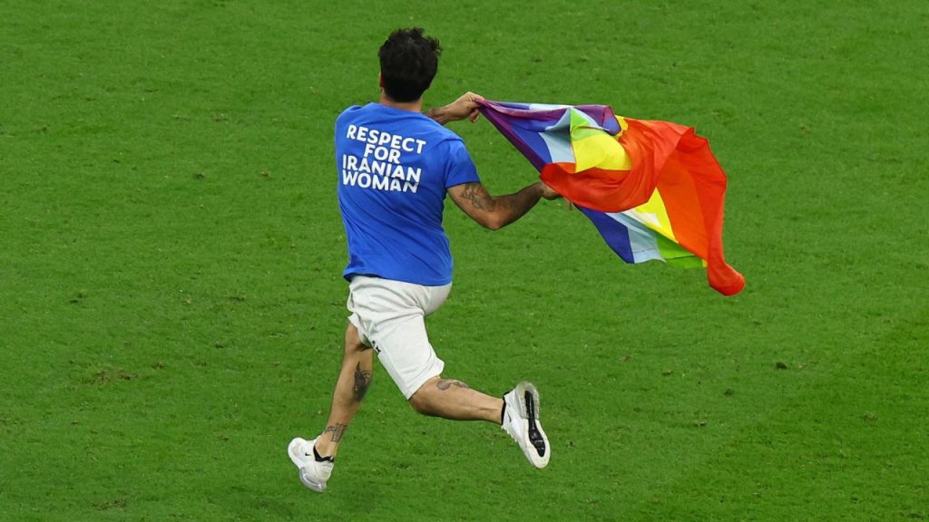 Pitch invader carrying a rainbow flag 