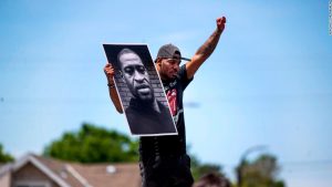 Tony L. Clark holds a photo of George Floyd outside the Cup Food convenience store, Thursday, May 28, 2020, in Minneapolis. Floyd, a handcuffed black man, died Monday in police custody near the convenience store. (Jerry Holt/Star Tribune via AP)